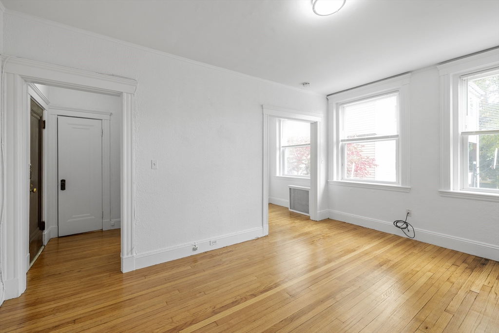 170 Maple Street, Unit 110 Malden, MA 02148 - Photo 3 of 23 an empty room with wooden floor and windows