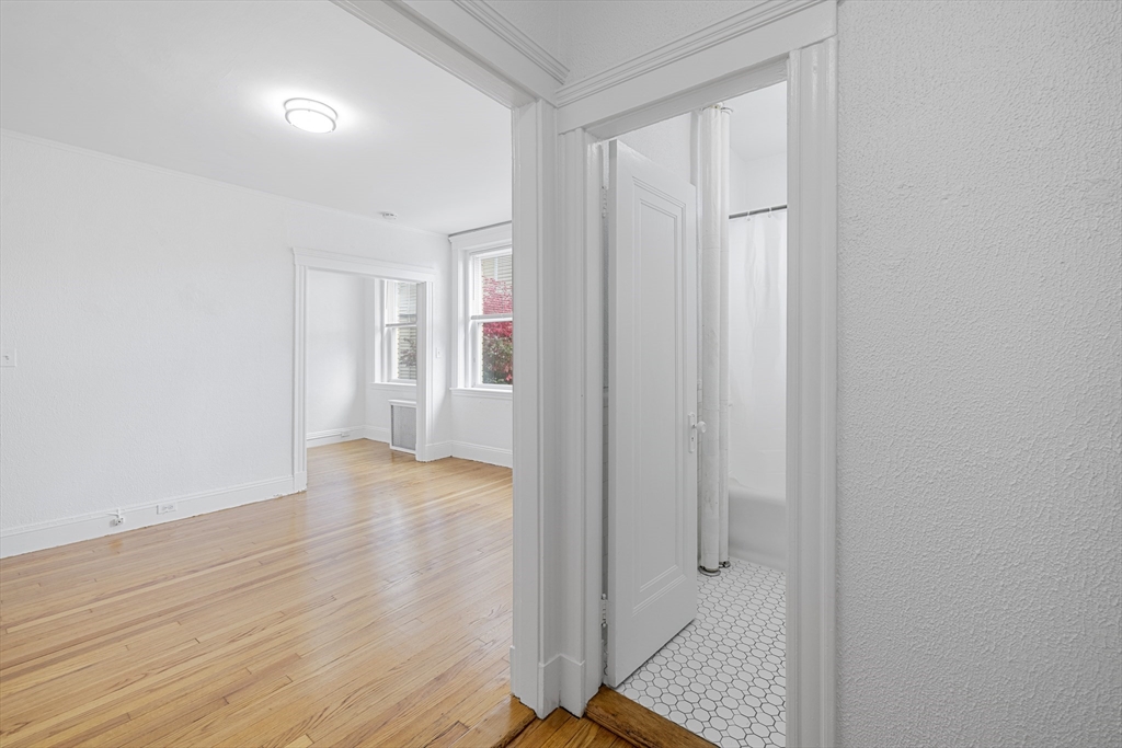 170 Maple Street, Unit 110 Malden, MA 02148 - Photo 5 of 23 an empty room with wooden floor and windows