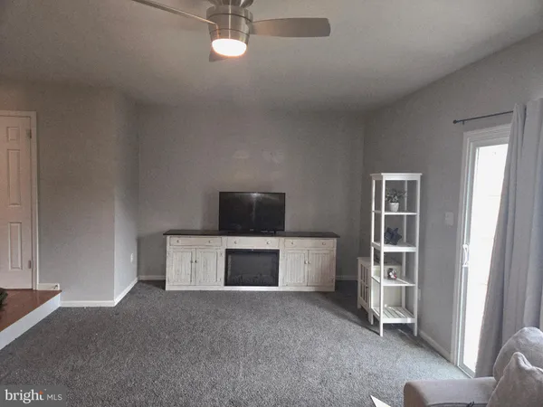 a living room with a fireplace and a ceiling fan