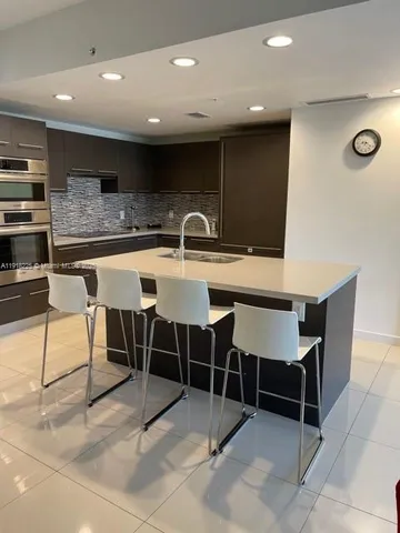 a kitchen with a dining table chairs and large window