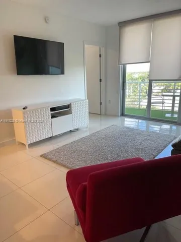 a living room with a bed furniture and a flat screen tv
