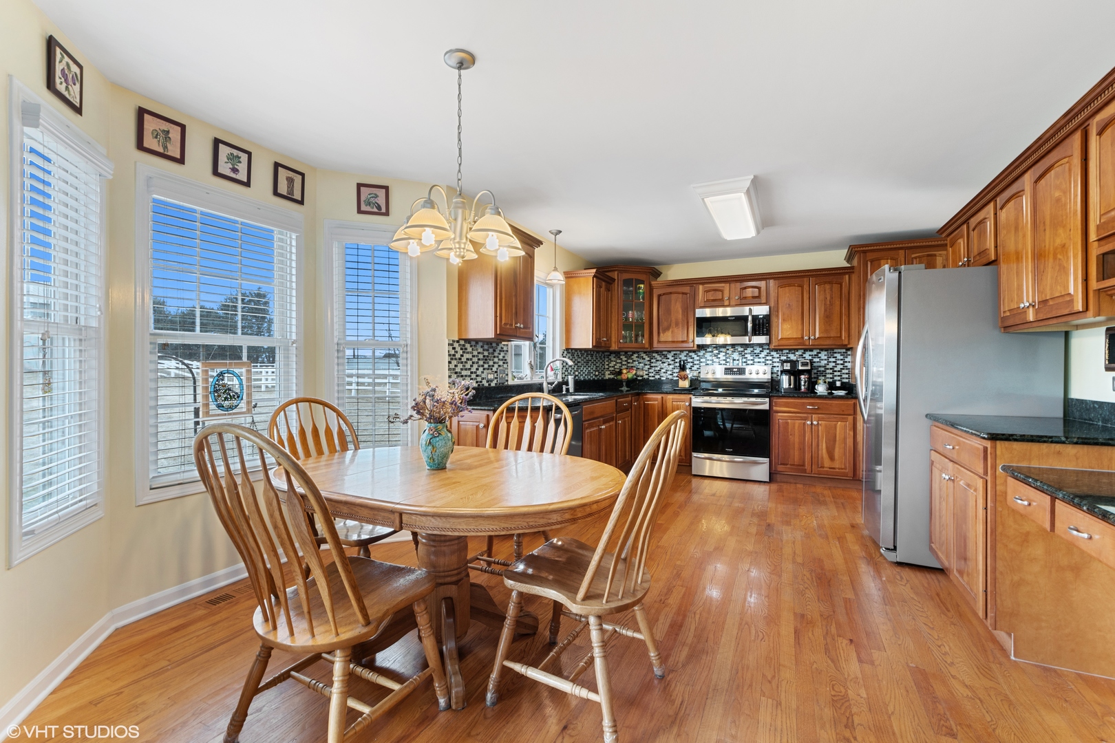 8734 West Offner Road Monee, IL 60449 - Photo 9 of 33 a kitchen with granite countertop a stove a sink a dining table and chairs