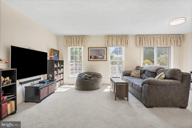 a living room with furniture a flat screen tv and a floor to ceiling window