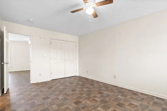 an empty room with a ceiling fan and a window