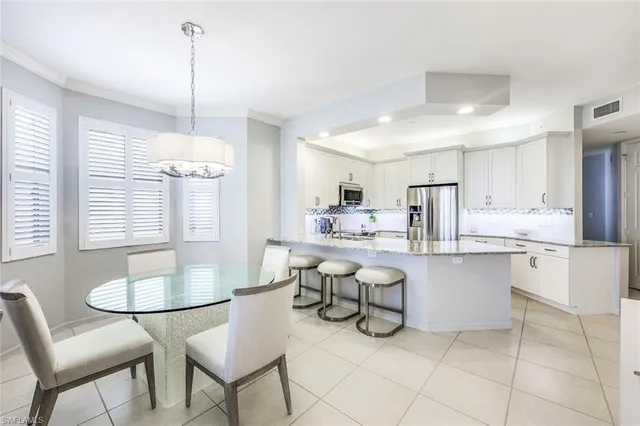 a kitchen with stainless steel appliances a table chairs and white cabinets