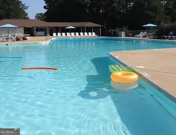 a view of a swimming pool with table and chairs under an umbrella