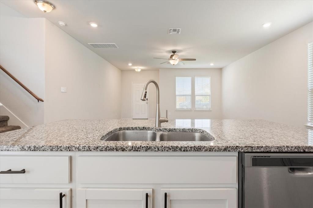 6317 Elephant Butte Drive Waco, TX 76708 - Photo 13 of 39 Kitchen island featuring a dual basin stainless steel sink with a pull-down faucet and granite countertop