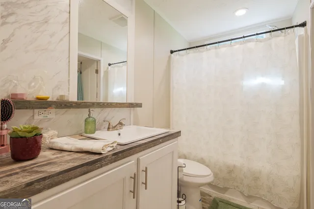 a bathroom with a granite countertop sink a toilet and a mirror