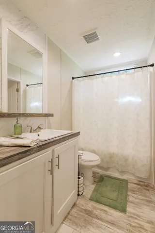 a bathroom with a sink a toilet a mirror and shower