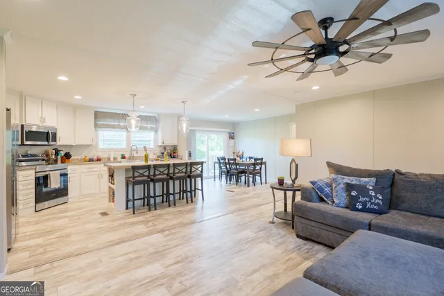 a living room with furniture kitchen view and a wooden floor