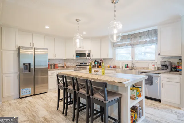 a kitchen with kitchen island granite countertop a sink a center island and stainless steel appliances
