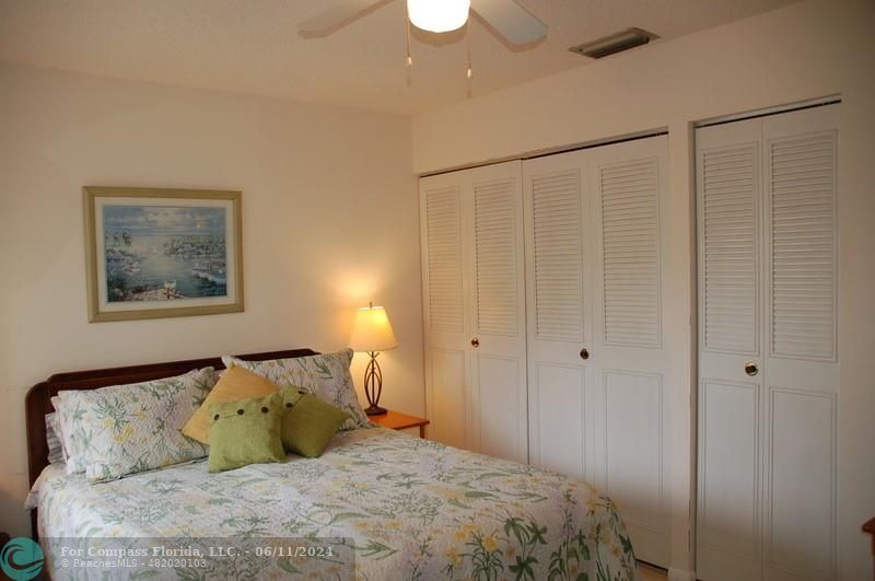 448 Pine Glen Lane, Unit E Greenacres, FL 33463 - Photo 16 of 35 a bedroom with a bed and a painting on the wall