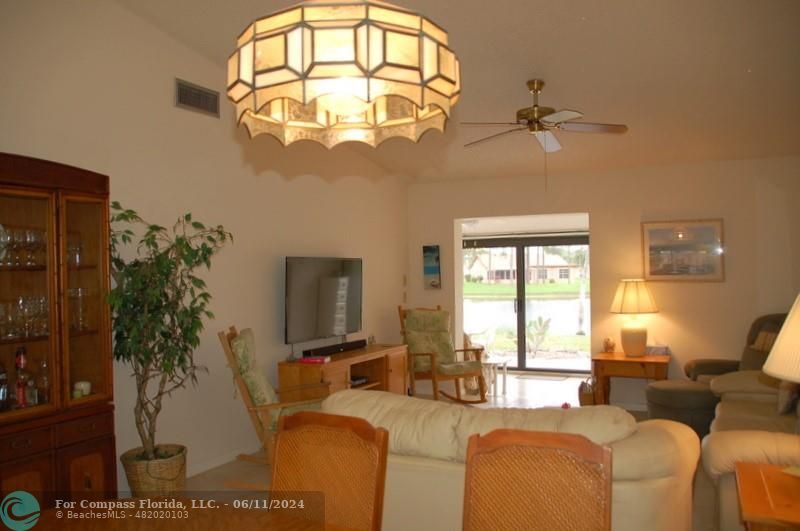 448 Pine Glen Lane, Unit E Greenacres, FL 33463 - Photo 5 of 35 a living room with furniture a chandelier and a flat screen tv