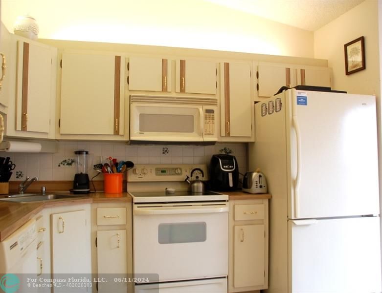 448 Pine Glen Lane, Unit E Greenacres, FL 33463 - Photo 8 of 35 a kitchen with stainless steel appliances white cabinets and a refrigerator