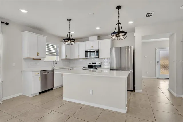 a kitchen with kitchen island stainless steel appliances a stove a refrigerator sink and cabinets