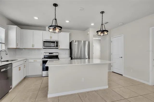 a kitchen with stainless steel appliances a refrigerator sink and white cabinets