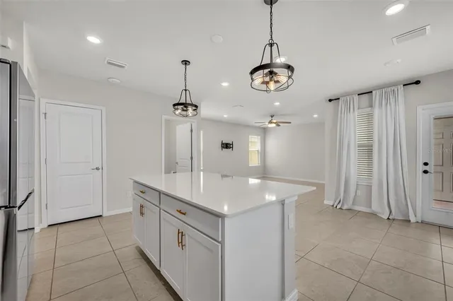 a large white kitchen with a large island oven a stove a refrigerator and a sink with wooden floor