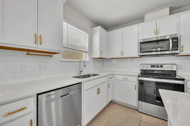 a kitchen with cabinets stainless steel appliances and sink