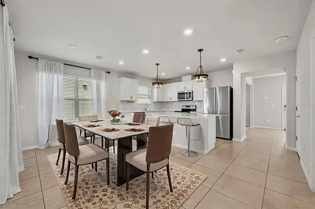 a kitchen with stainless steel appliances kitchen island granite countertop a dining table chairs and sink