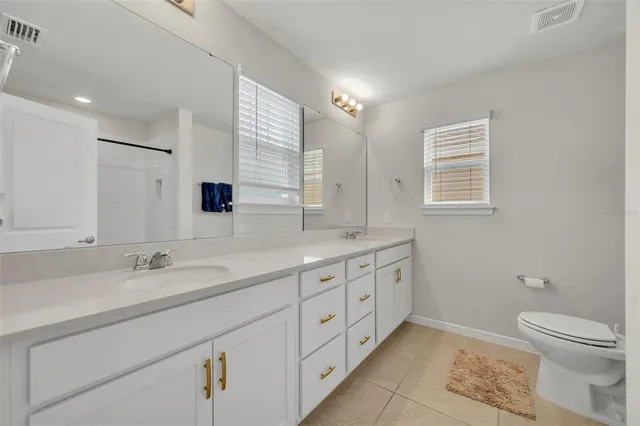 a bath room with a toilet a sink a mirror and a shower