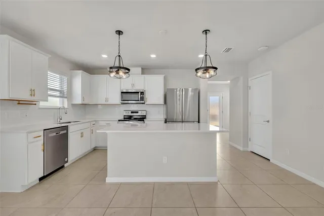 a large kitchen with granite countertop a stove a sink dishwasher a refrigerator and a oven with wooden floor