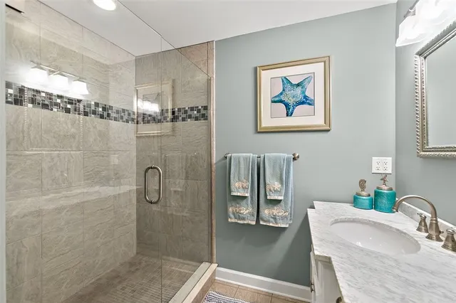 a bathroom with a granite countertop shower a sink and a mirror