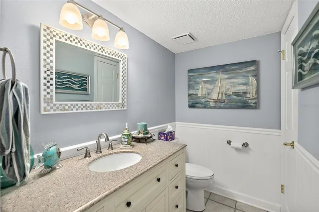 a bathroom with a granite countertop toilet a sink a mirror and a window