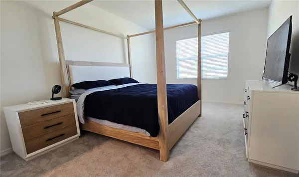 a bedroom with a bed and a flat tv screen on dresser