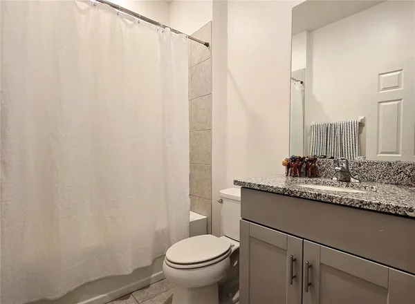 a bathroom with a granite countertop sink toilet and a mirror