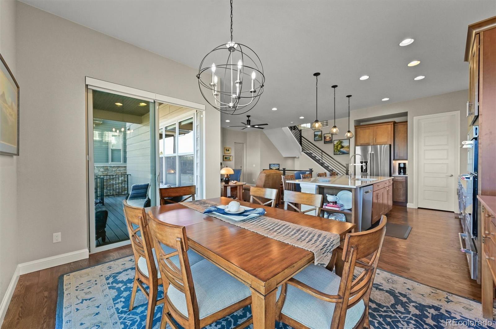 493 Meadowleaf Lane Highlands Ranch, CO 80126 - Photo 13 of 48 a dining room with wooden floor a chandelier a wooden table and chairs