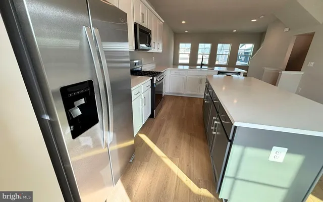 a kitchen with stainless steel appliances a refrigerator a sink a stove a microwave cabinets and furniture