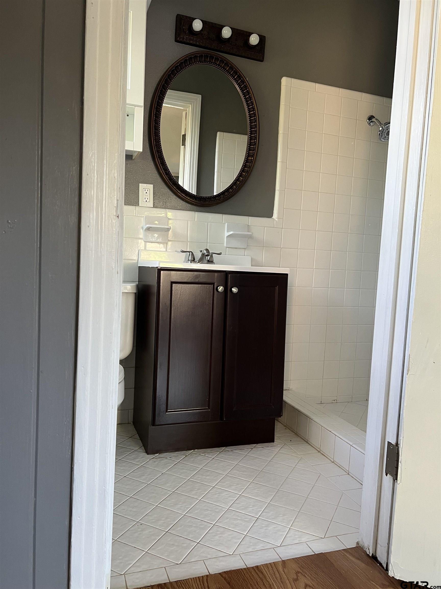 1223 South Azalea Drive Tyler, TX 75701 - Photo 11 of 11 a bathroom with a granite countertop mirror and a sink