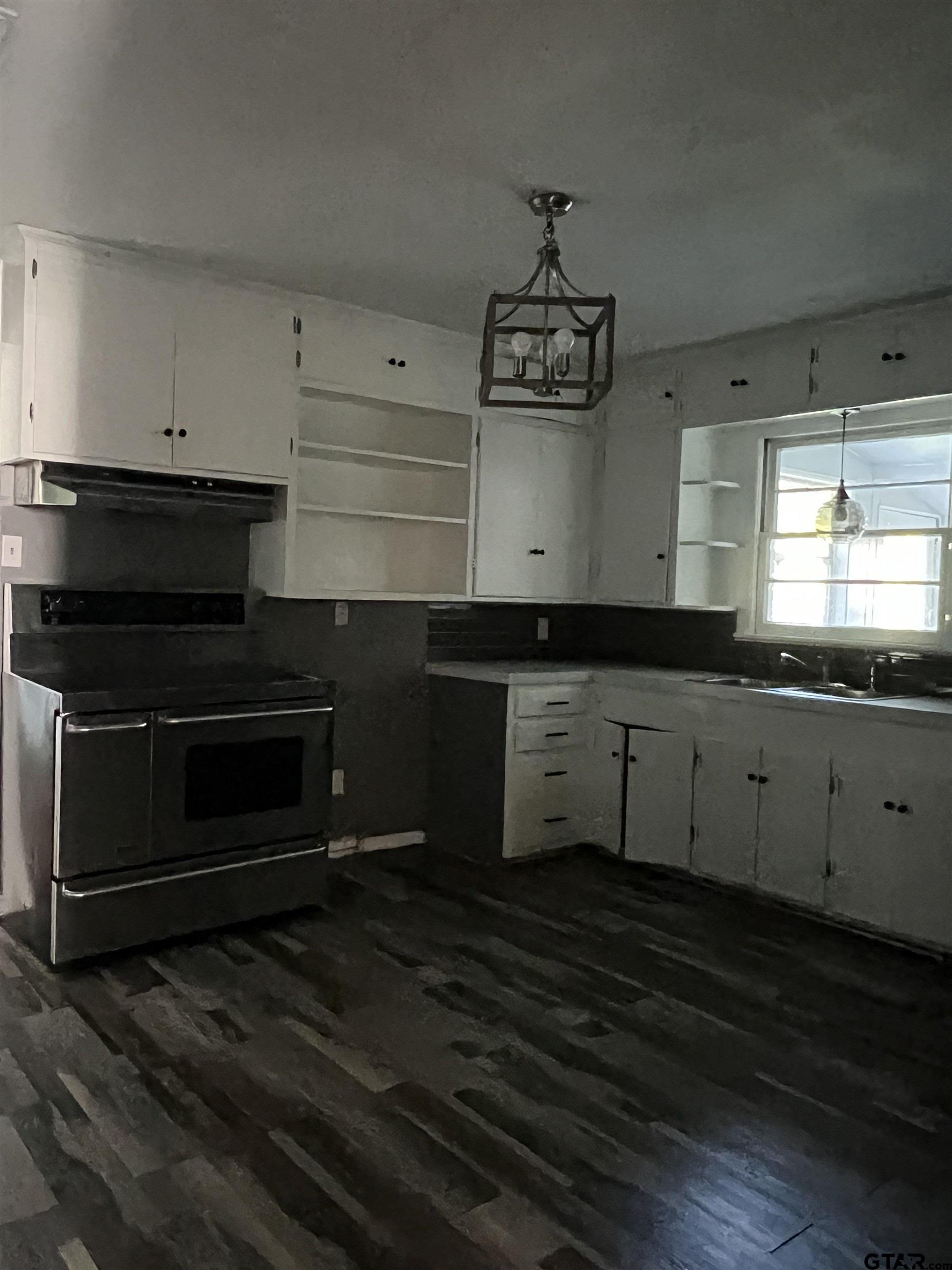 1223 South Azalea Drive Tyler, TX 75701 - Photo 3 of 11 a kitchen with a stove and white cabinets