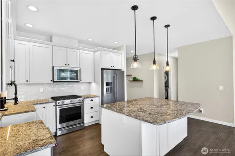 a kitchen with stainless steel appliances granite countertop a stove a sink and a refrigerator