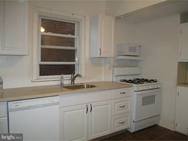 a kitchen with white cabinets and appliances