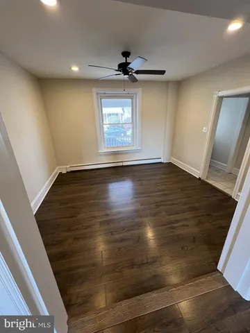 an empty room with wooden floor fan and window