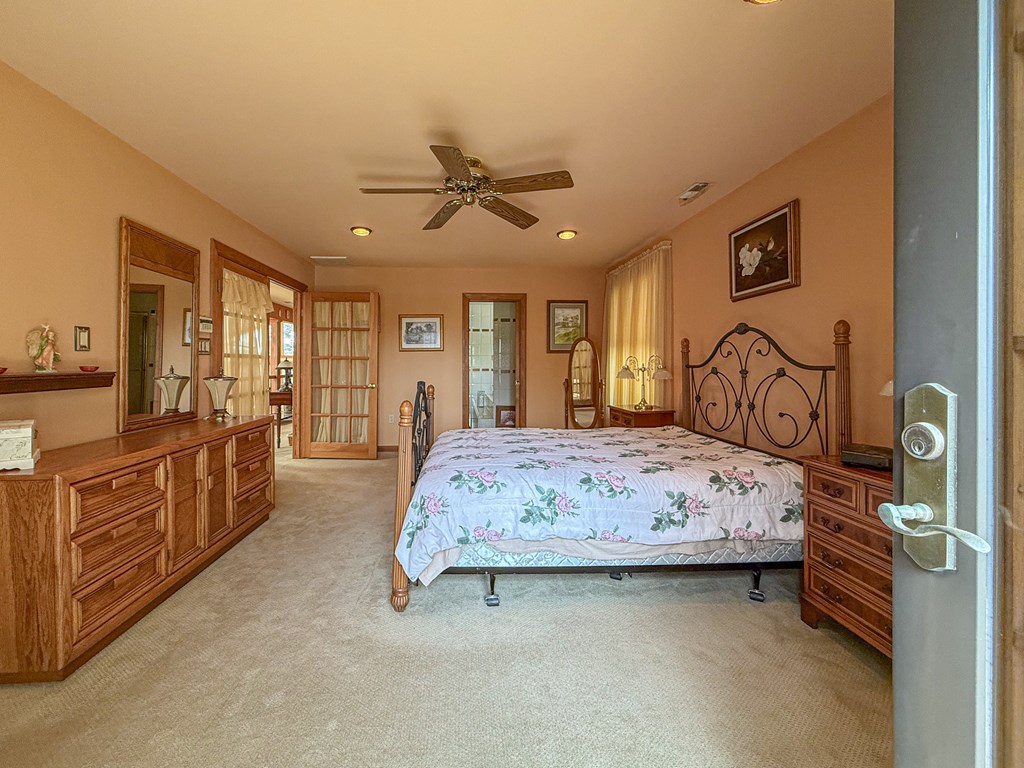 13581 Solitude Trail Machipongo, VA 23405 - Photo 16 of 51 a bedroom with a bed a chandelier with dresser and mirror