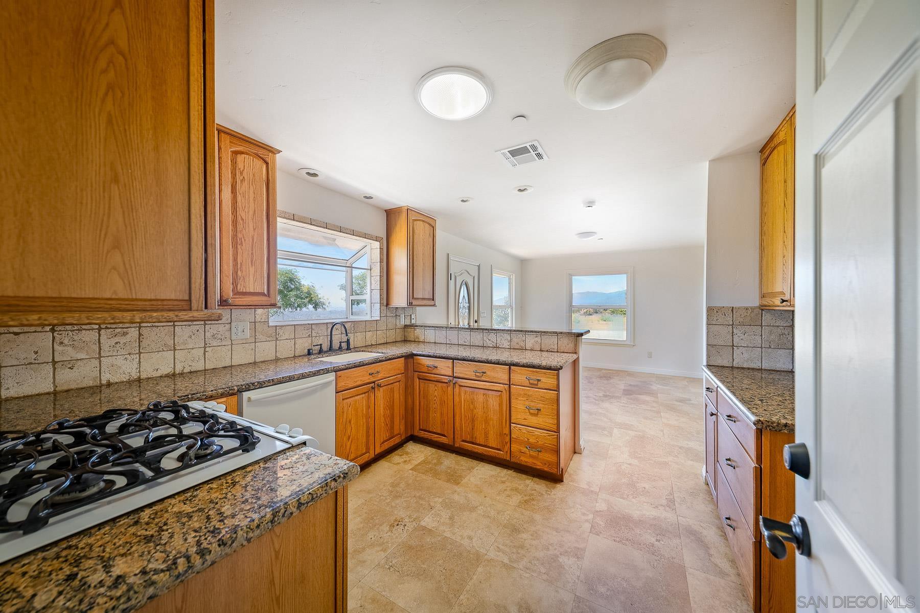 38960 Magee Road Pala, CA 92059 - Photo 9 of 25 a kitchen with stainless steel appliances granite countertop a stove a sink and a refrigerator