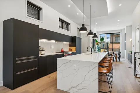 a kitchen with stainless steel appliances kitchen island granite countertop a refrigerator a stove and a sink with wooden floor