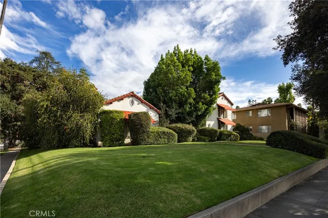 a view of a white house with a big yard and a large tree