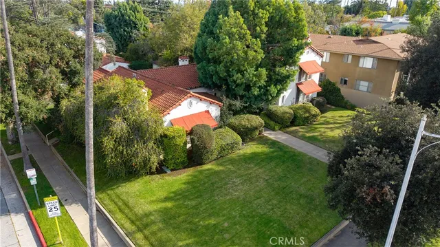 an aerial view of residential houses with outdoor space and trees