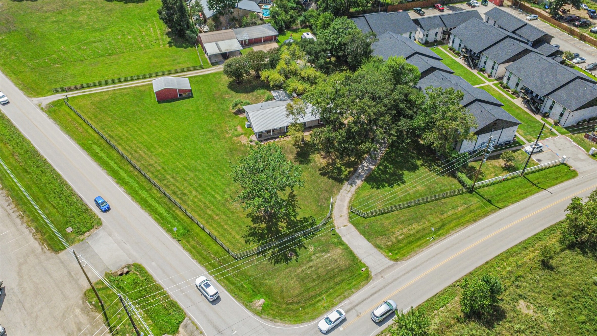 307 West Hufsmith Road Tomball, TX 77375 - Photo 3 of 44 Expansive corner lot featuring lush green lawns, a charming red barn, and a cozy single-story home surrounded by mature trees, offering privacy and a serene setting.