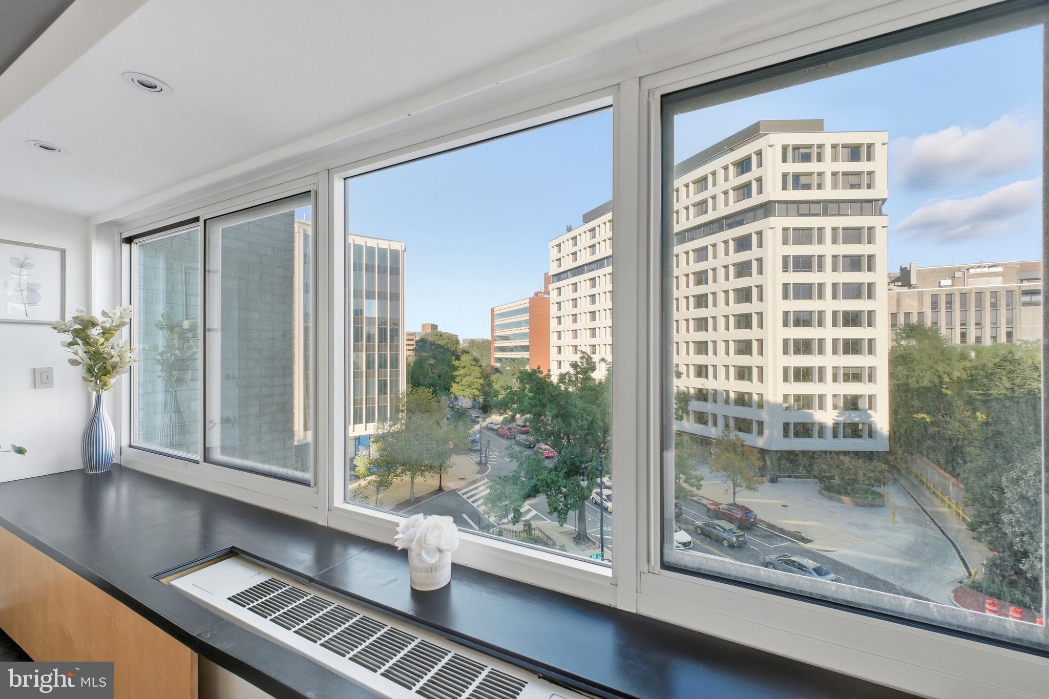 a view of a room that has a large window and wooden floor