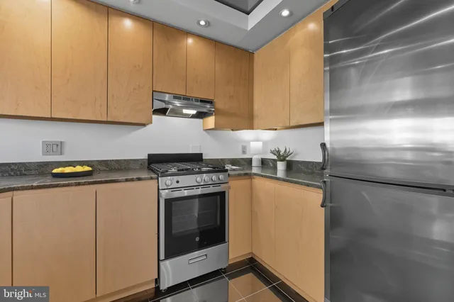 a kitchen with stainless steel appliances granite countertop a refrigerator a sink a stove and white cabinets