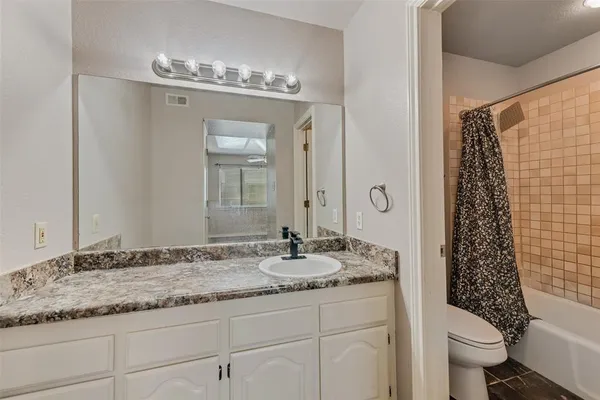 a bathroom with a granite countertop sink a toilet and a shower