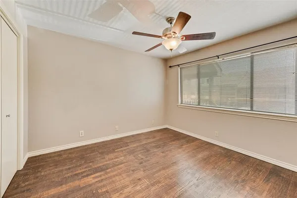 an empty room with wooden floor fan and windows