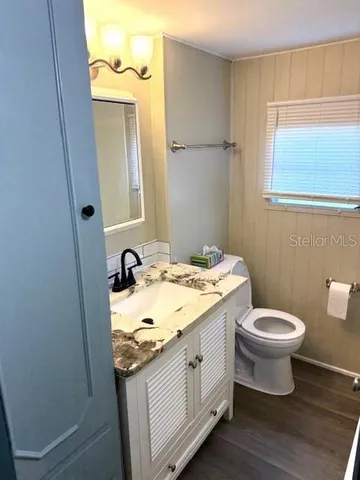 a bathroom with a granite countertop sink toilet and mirror