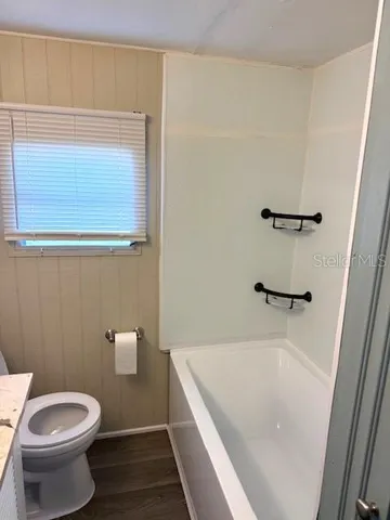 a bathroom with a granite countertop bathtub shower and toilet