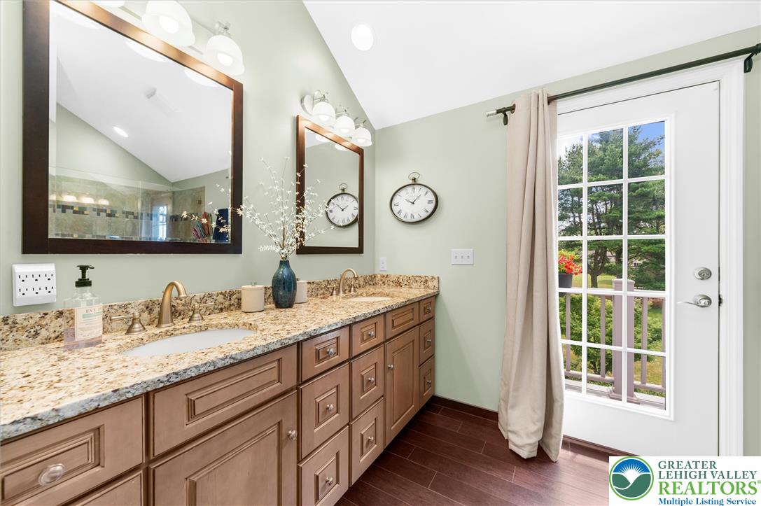5616 Snowdrift Road Orefield, PA 18069 - Photo 16 of 36 Dual vanities with granite counters and rich wood cabinetry, all illuminated by a windowed door to the outdoors.
