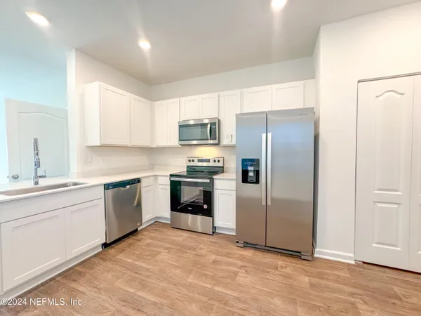 a kitchen with granite countertop a refrigerator and a stove top oven